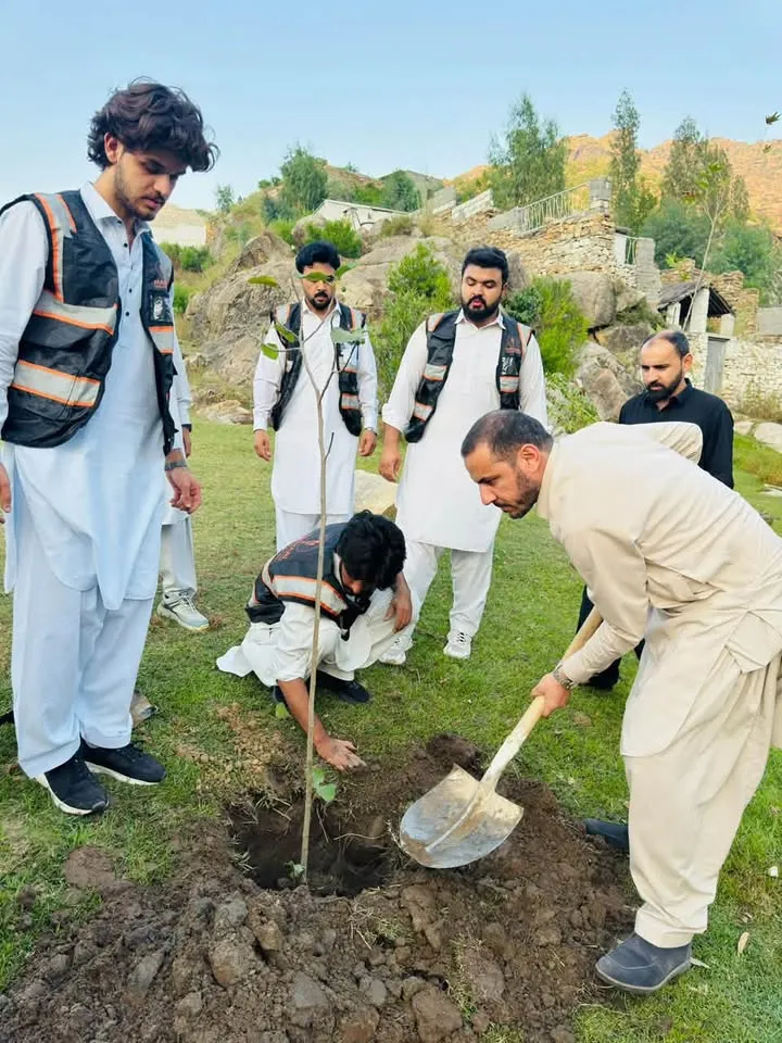 Volunteers digging in a sapling on open ground during a plantation drive.
