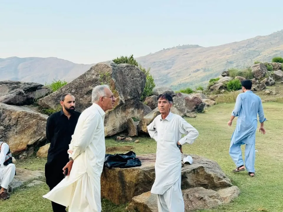 Volunteers on open ground below the hills of Malakand.
