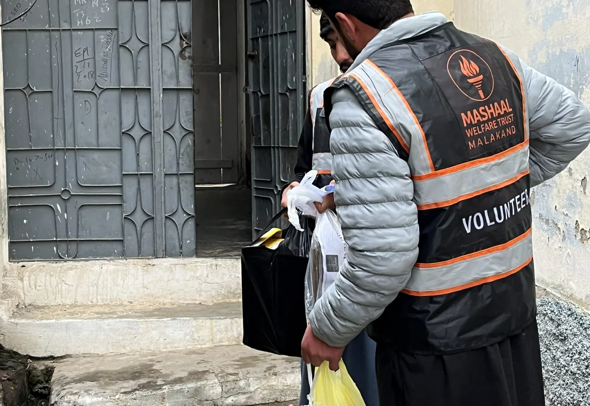 A Mashaal volunteer delivering a package at a household door in Thana.