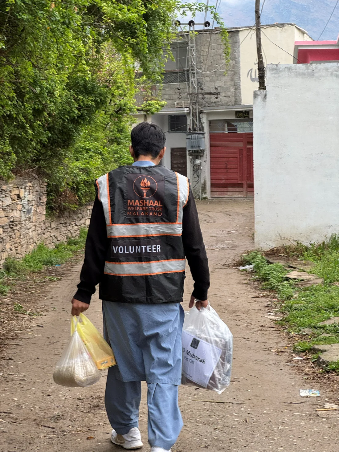 A volunteer carrying parcels up a village lane in Thana.